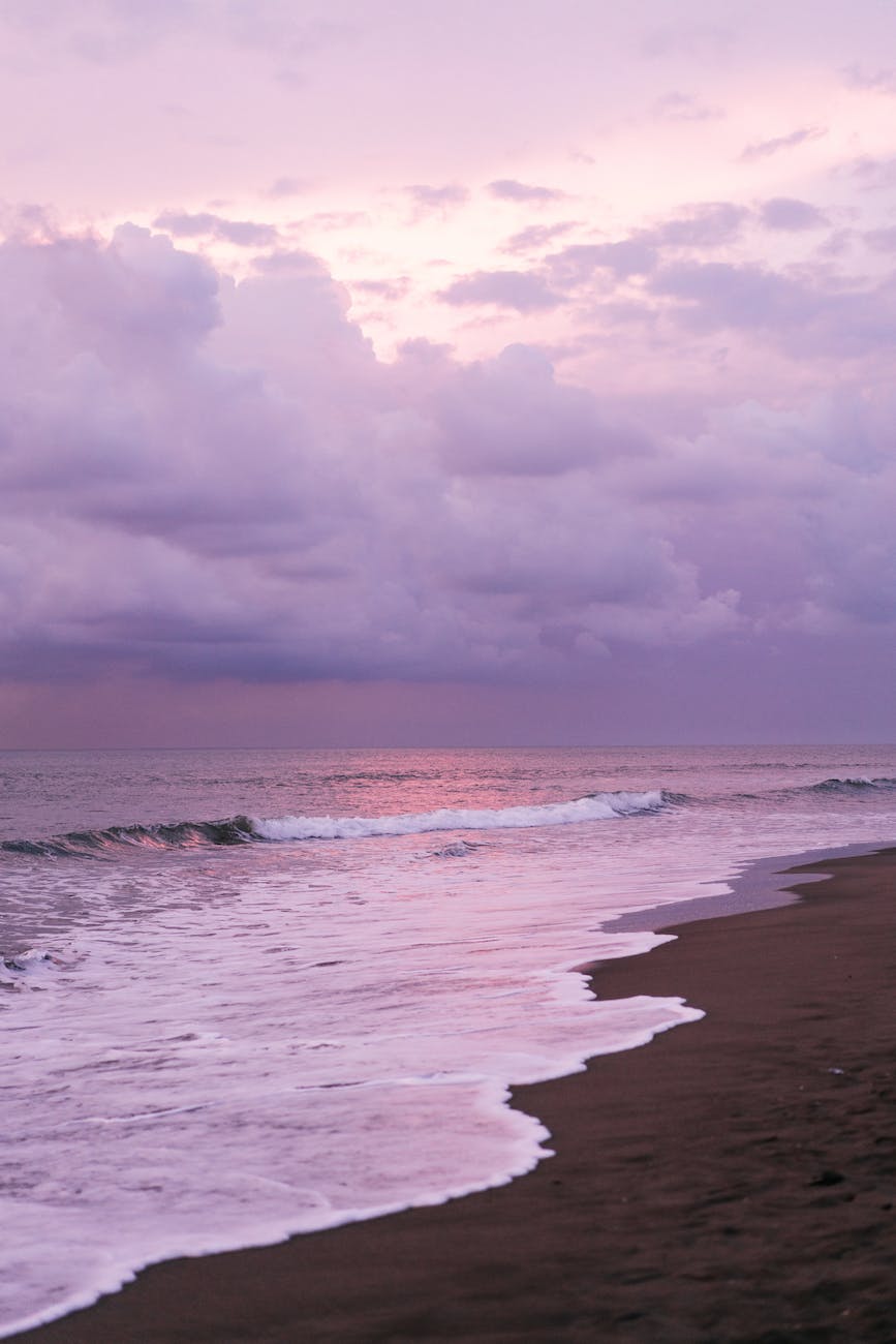 waving sea and sandy shore against purple sky