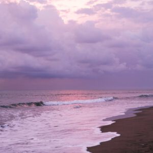 waving sea and sandy shore against purple sky